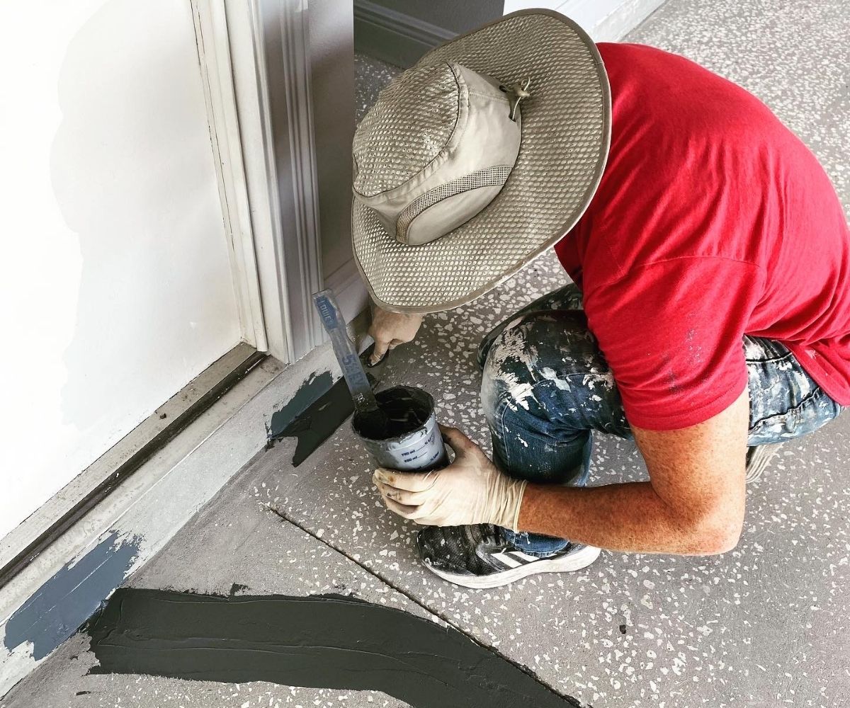 Caulking and sealing a garage door threshold as part of a concrete coating installation in Saint Augustine, Florida