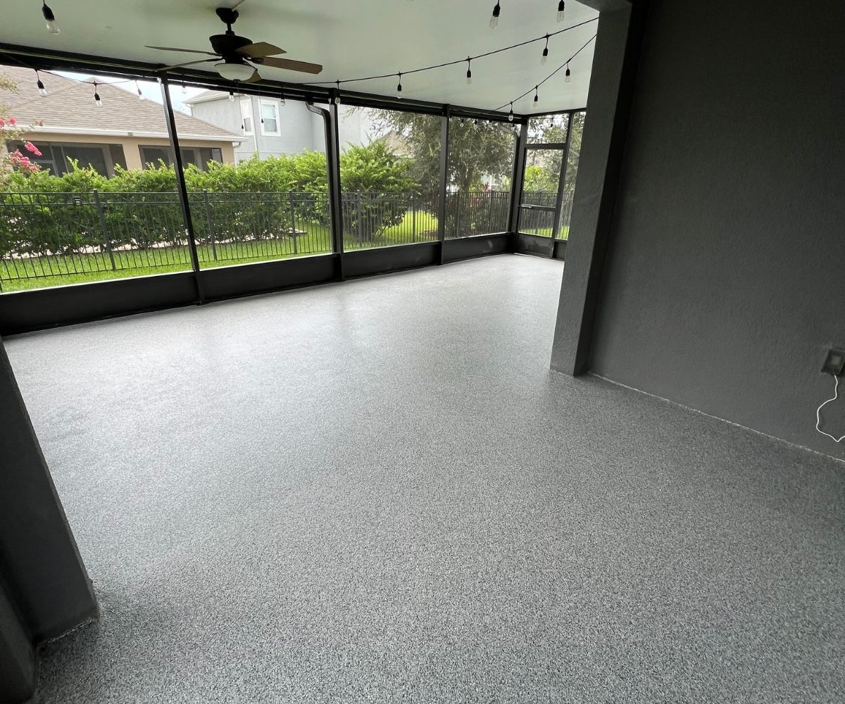 Gray flake concrete coating on a screened lanai floor with string lights in Saint Augustine, Florida