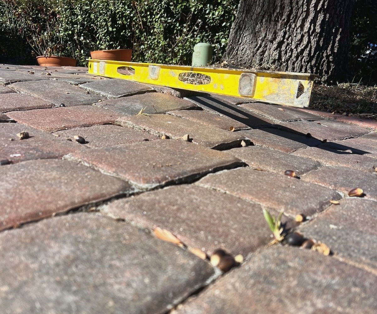 Checking a paver patio for settling with a level during inspection in Saint Augustine, Florida