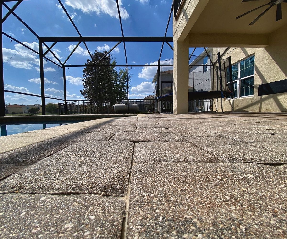 Weathered, unsealed pool deck pavers showing sun fading and worn joints in Saint Augustine, Florida